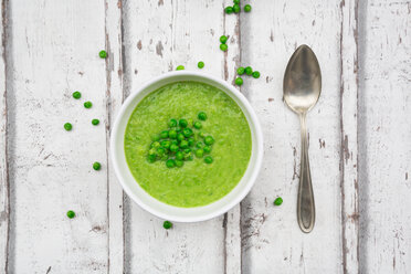 Schüssel mit Erbsensuppe, Löffel und Erbsen auf Holz - LVF06586