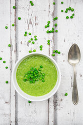 Schüssel mit Erbsensuppe, Löffel und Erbsen auf Holz - LVF06587