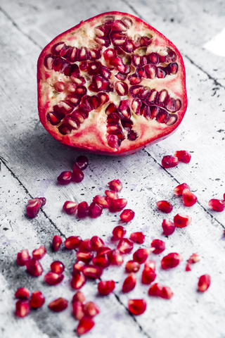 Sliced pomegranate and pomegranate seed on wood stock photo