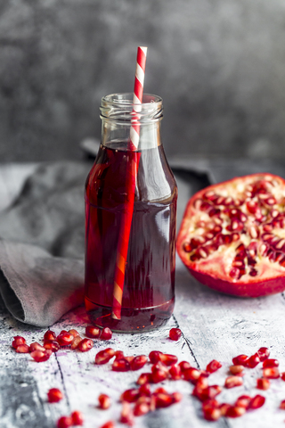 Glass bottle of pomegranate juice and sliced pomegranate stock photo