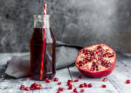 In Scheiben geschnittener Granatapfel und Glasflasche mit Granatapfelsaft - SARF03456