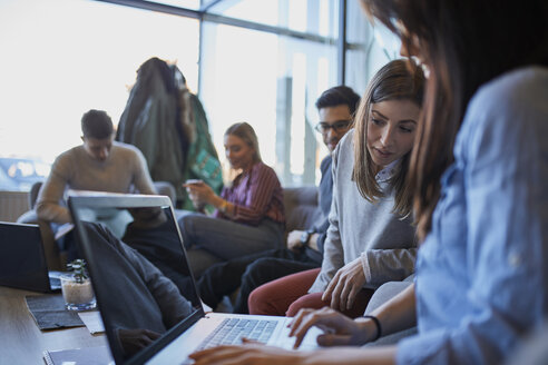 Eine Gruppe von Freunden sitzt mit einem Laptop in einem Café zusammen - ZEDF01035