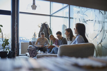 Eine Gruppe glücklicher Freunde sitzt in einem Café mit Laptop und Dokumenten zusammen - ZEDF01043