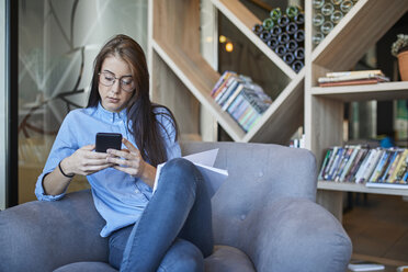 Junge Frau sitzt im Café und benutzt ihr Smartphone - ZEDF01046