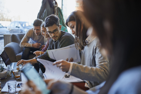 Group of friends sitting together in a cafe with laptop and documents stock photo