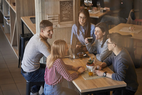Gruppe glücklicher Freunde, die in einem Café mit Laptop und Getränken zusammensitzen - ZEDF01059