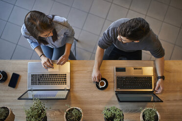 Top view of young woman and man in a cafe with laptops discussing - ZEDF01067