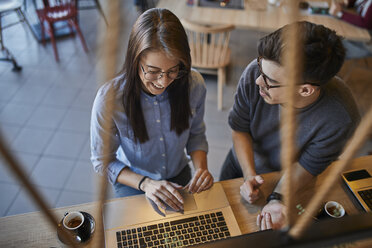 Young man looking at smiling woman in a cafe with laptop - ZEDF01070