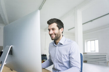 Smiling businessman working at desk in office - MOEF00639