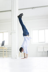 Geschäftsmann macht einen Handstand im Büro - MOEF00640