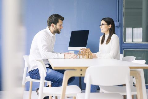 Man and woman talking with architectural model on table stock photo