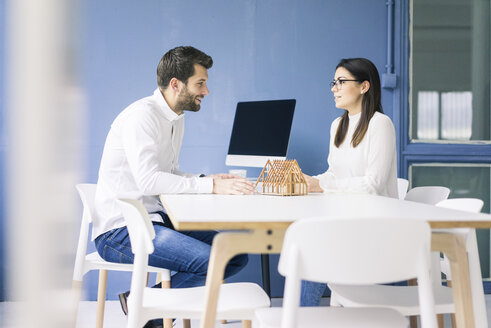 Mann und Frau unterhalten sich mit einem Architekturmodell auf einem Tisch - MOEF00648