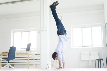 Geschäftsmann macht einen Handstand im Büro - MOEF00651