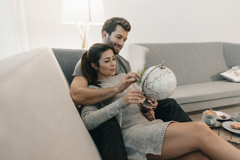 Ehepaar entspannt sich auf der Couch zu Hause und betrachtet den Globus - MOEF00693