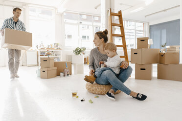 Family moving into new home with father carrying cardboard box - KNSF03389