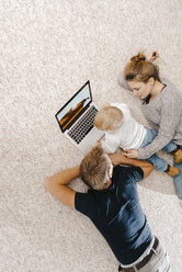Familie benutzt Laptop auf dem Teppich - KNSF03390