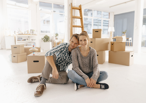 Porträt eines lächelnden Paares beim Einzug in ein neues Haus, lizenzfreies Stockfoto