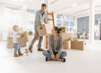 Happy family moving into new home with father and daughter carrying cardboard boxes - KNSF03402