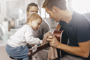 Kleines Mädchen untersucht die Gitarre des Vaters zu Hause - KNSF03407