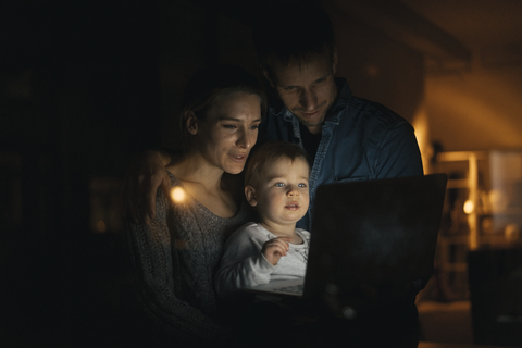 Familie benutzt Laptop in der Dunkelheit, lizenzfreies Stockfoto