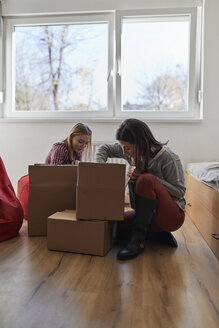 Zwei junge Frauen packen Kartons in einem Zimmer aus - ZEDF01080