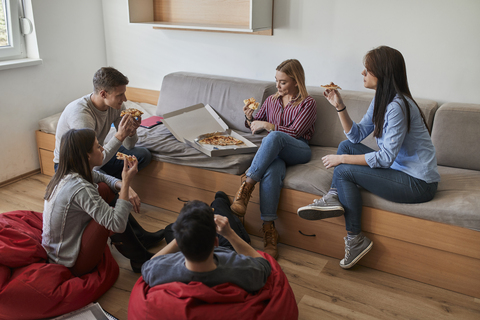 Group of students in dormitory eating pizza together stock photo
