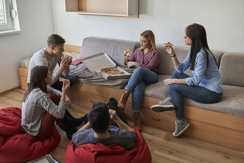 Gruppe von Studenten in einem Schlafsaal, die gemeinsam Pizza essen, lizenzfreies Stockfoto