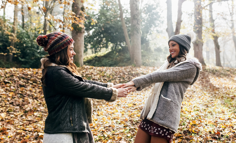 Zwei hübsche Frauen haben Spaß in einem herbstlichen Wald, lizenzfreies Stockfoto