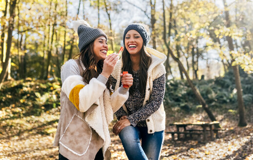 Zwei schöne Frauen haben Spaß mit Seifenblasen in einem herbstlichen Wald - MGOF03707