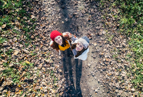 Zwei glückliche Frauen stehen auf einem herbstlichen Waldweg, lizenzfreies Stockfoto