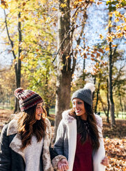Zwei hübsche Frauen lächeln sich in einem herbstlichen Wald an - MGOF03724