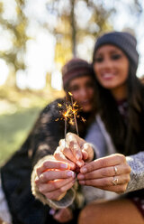 Hands of two women holding sparklers outdoors - MGOF03729