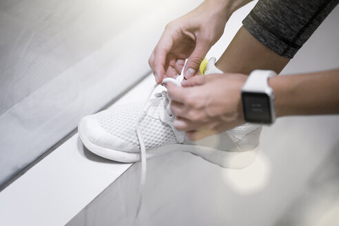 Close up of female hands tying sneakers with smartwatch - SBOF00988