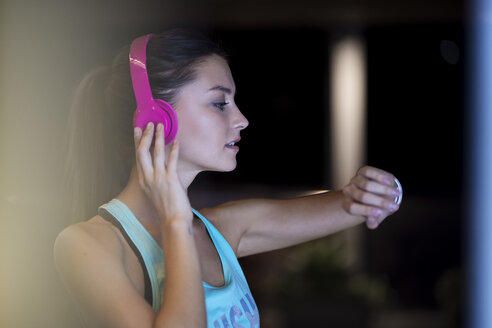 Junge Frau mit rosa Kopfhörern überprüft ihre Smartwatch - SBOF01008