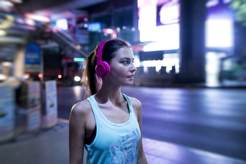 Junge Frau im rosa Sporthemd in moderner städtischer Umgebung bei Nacht, lizenzfreies Stockfoto