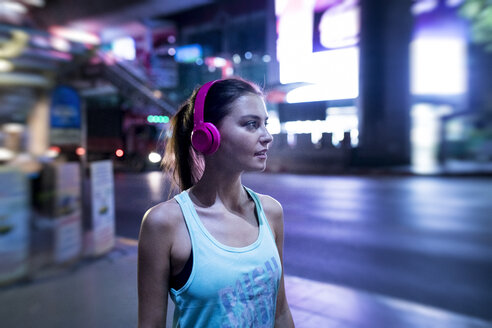 Young woman in pink sportshirt in modern urban setting at night - SBOF01010