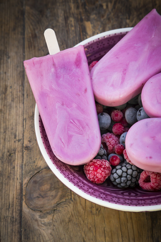 Homemade wild-berry ice lollies with raspberries, blueberries, red currants and blackberries in a bowl stock photo