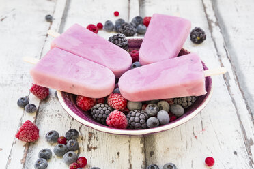 Homemade wild-berry ice lollies with raspberries, blueberries, red currants and blackberries in a bowl - LVF06601
