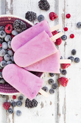 Homemade wild-berry ice lollies with raspberries, blueberries, red currants and blackberries in a bowl - LVF06602