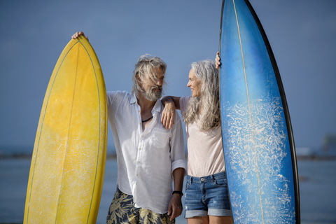 Zärtliches älteres Paar mit Surfbrettern am Strand, lizenzfreies Stockfoto