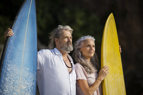 Zärtliches älteres Paar mit Surfbrettern am Strand, lizenzfreies Stockfoto