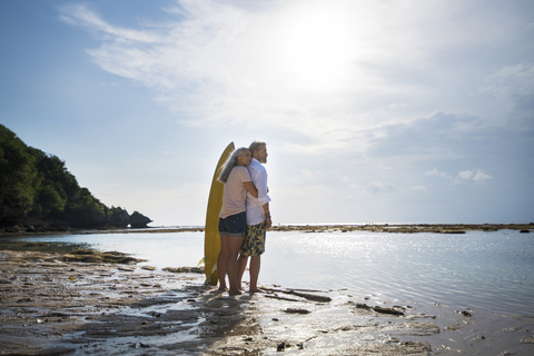 Zärtliches älteres Paar mit Surfbrettern am Strand, lizenzfreies Stockfoto