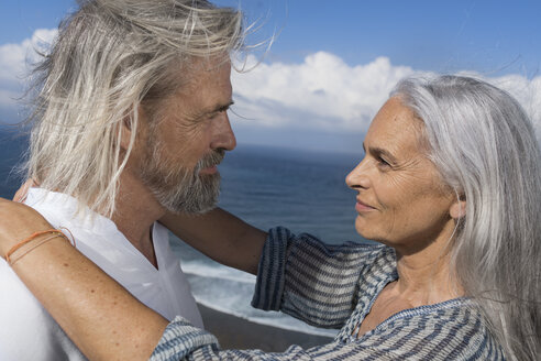 Zärtliches älteres Paar, das sich vor dem Meer in die Augen schaut - SBOF01063