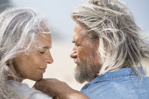 Zärtliches älteres Paar, das sich vor dem Meer in die Augen schaut - SBOF01067
