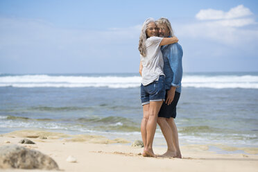 Affectionate senior couple standing on the beach - SBOF01075