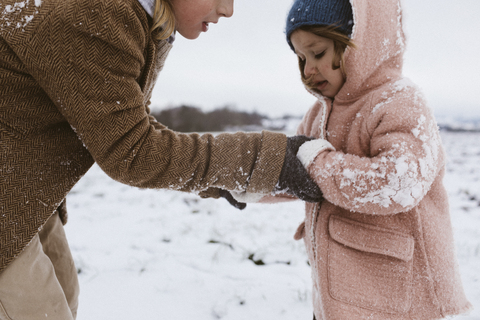 Brother and little sister together on snow-covered meadow stock photo