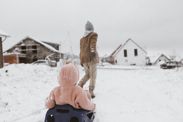 Junge zieht Schlitten mit kleiner Schwester im Schnee - KMKF00129