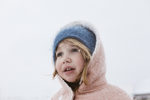 Porträt eines kleinen Mädchens im Schneefall, lizenzfreies Stockfoto