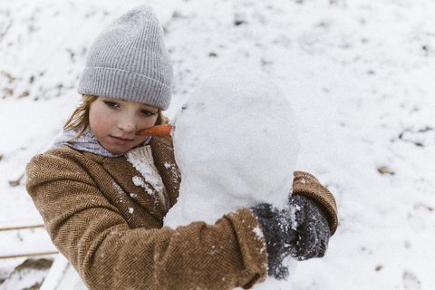 Junge, der einen Schneemann umarmt, lizenzfreies Stockfoto
