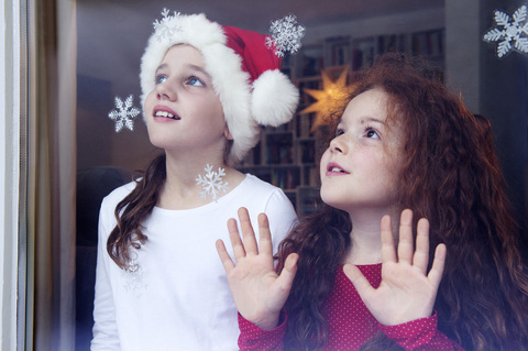 Kleine Mädchen stehen am Fenster und warten auf Weihnachten, lizenzfreies Stockfoto